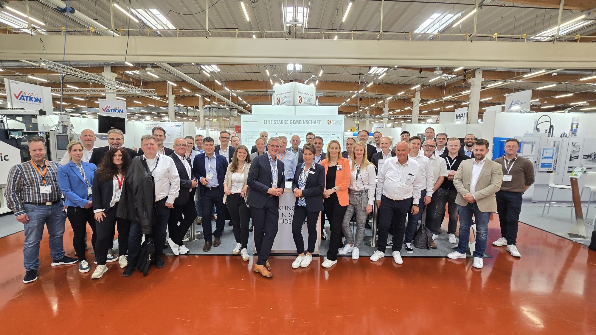 Gruppe von Ausstellern und Fachbesuchern am Gemeinschaftsstand des Kunststoff-Instituts auf einer Kunststoffmesse