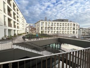 Blick in den Innenbereich des Mixed-Use-Quartiers Perlach Plaza in München mit Wohngebäuden, Wegen und Treppenanlage