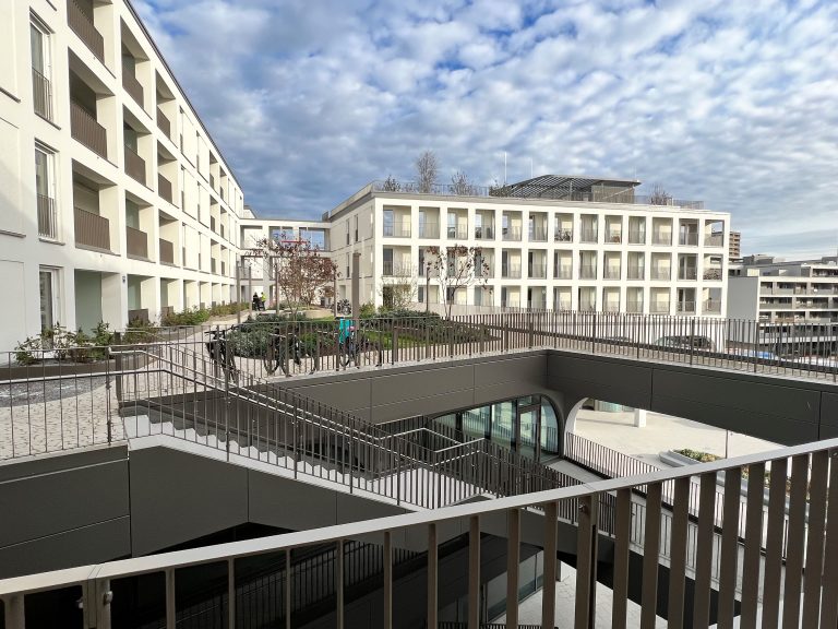 Blick in den Innenbereich des Mixed-Use-Quartiers Perlach Plaza in München mit Wohngebäuden, Wegen und Treppenanlage