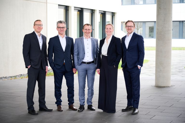 Geschäftsleitung von exxis vor einem modernen Unternehmensgebäude