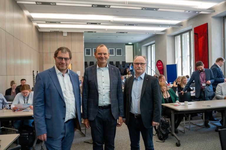 Professor Stefan Witte, TH-OWL-Präsident Jürgen Krahl und Institutsleiter Thomas Schulte stehen bei der FJRG-Fachtagung im historischen Rathaus Lemgo vor den Teilnehmenden.