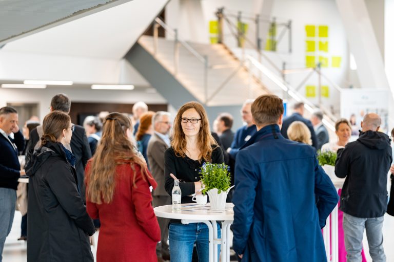 Besucherinnen und Besucher des HWM Update 2026 sprechen an Stehtischen im Veranstaltungsgebäude der Hochschule Osnabrück.