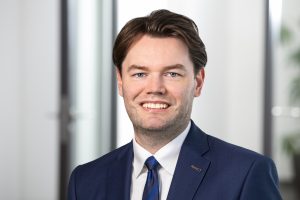 Porträt von Niels Morgenstern im dunkelblauen Anzug vor hellem Bürohintergrund