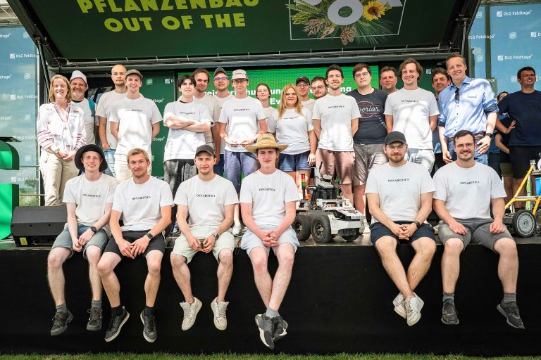 Das Team Acorn von Osnabotics steht mit Feldrobotern auf der Bühne der DLG-Feldtage.
