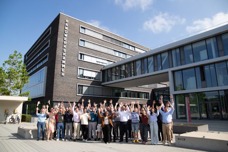 Teilnehmende des Makeathon Future Energies mit erhobenen Händen vor der Handwerkskammer OWL in Bielefeld