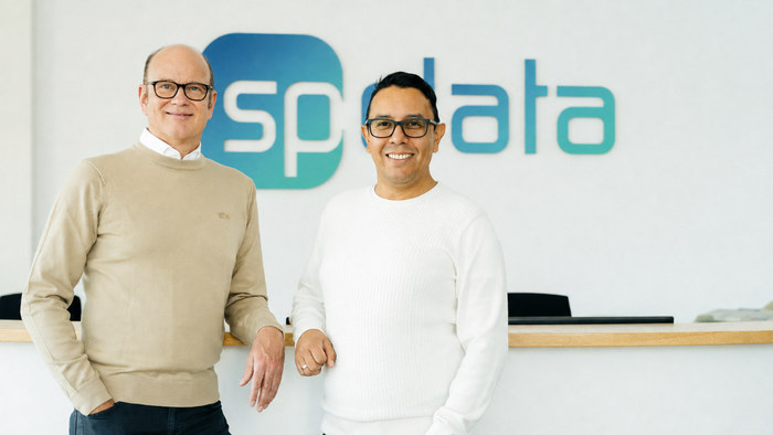 Die erweiterte Geschäftsführung von SP_Data vor dem Unternehmenslogo