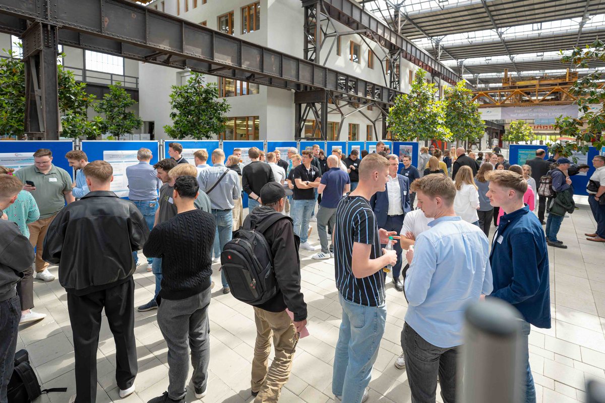 Teilnehmende tauschen sich an Projektpostern in der Halle des Campus Lingen aus.