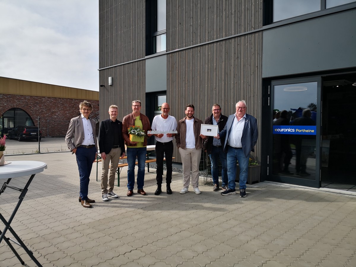 Hermann Portheine und Dennis Gösling mit Gästen vor dem neuen Unternehmensgebäude in Lingen-Brögbern