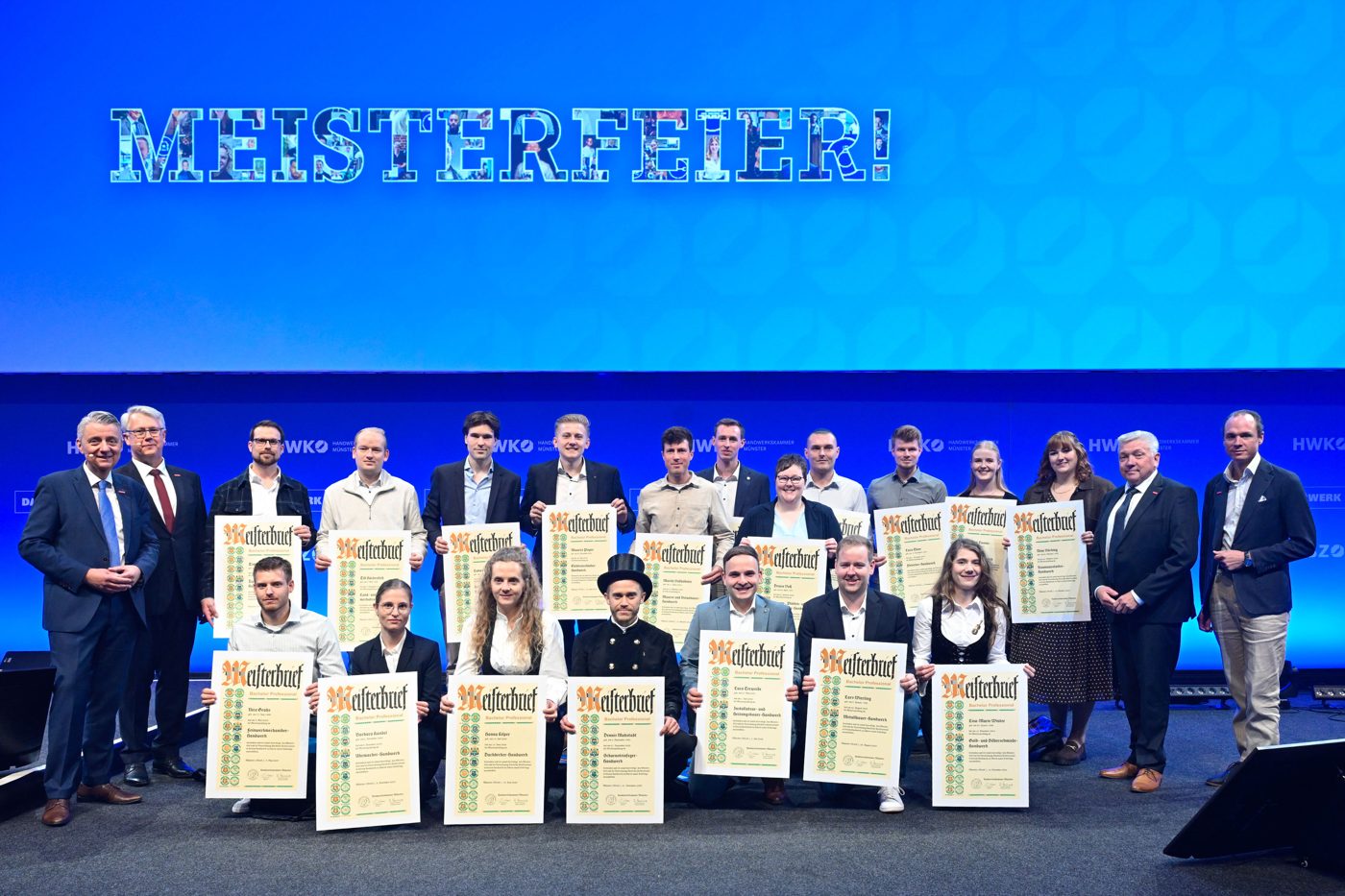 Ausgezeichnete Meisterinnen und Meister mit ihren Meisterbriefen auf der Bühne der HWK-Meisterfeier in Münster.