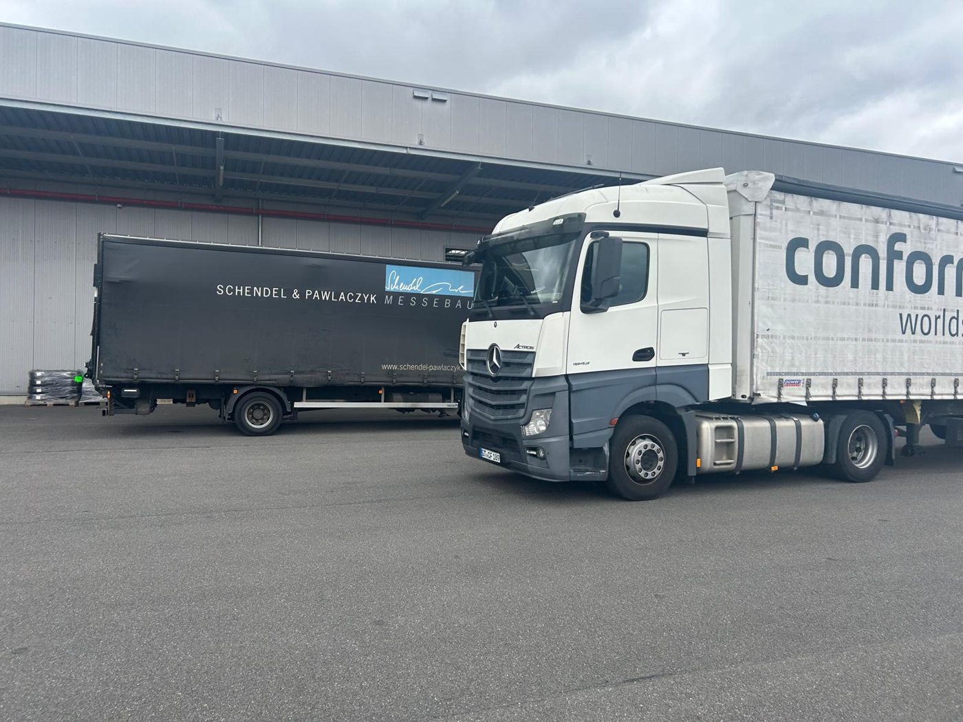 Lkw von Schendel & Pawlaczyk und conform vor einer Lagerhalle.